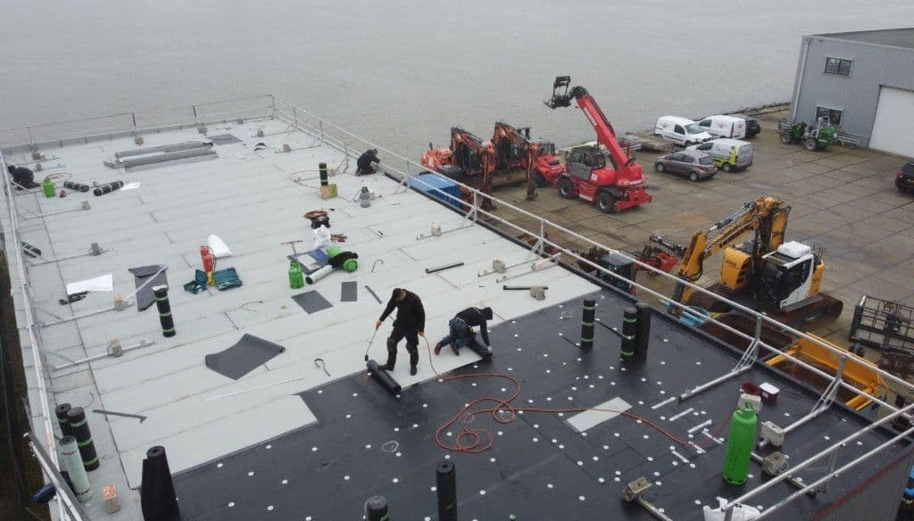 Dakdekkers aan het werk op een groot plat dak